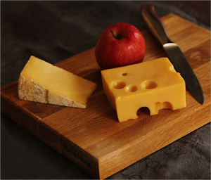 Cheese on a board with apple and knife